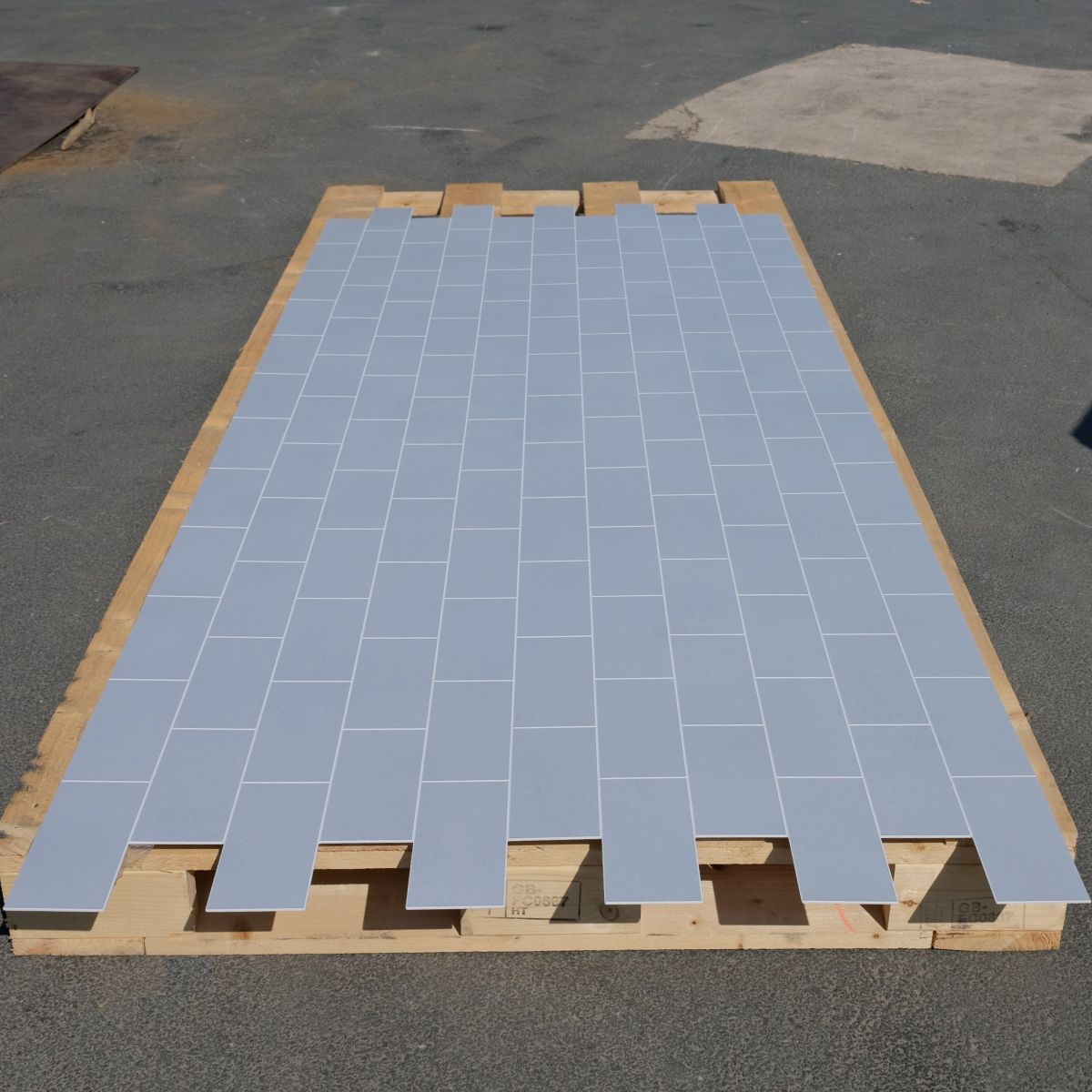 Pallet with PVC sheet with cement grey tiles on a tarmac surface